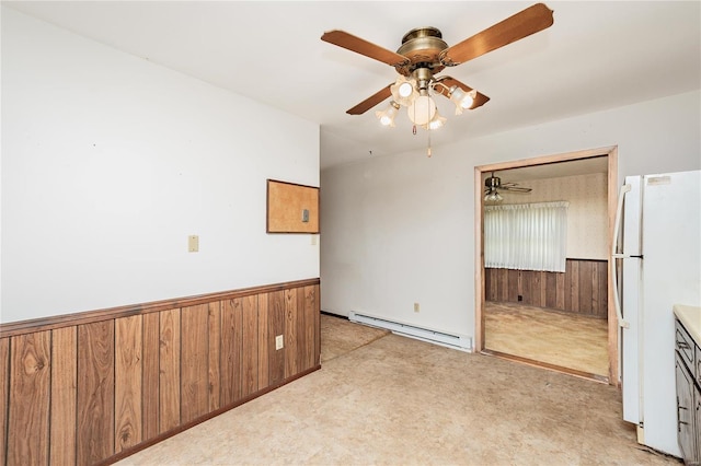 unfurnished room with wainscoting, wooden walls, light colored carpet, and a baseboard radiator
