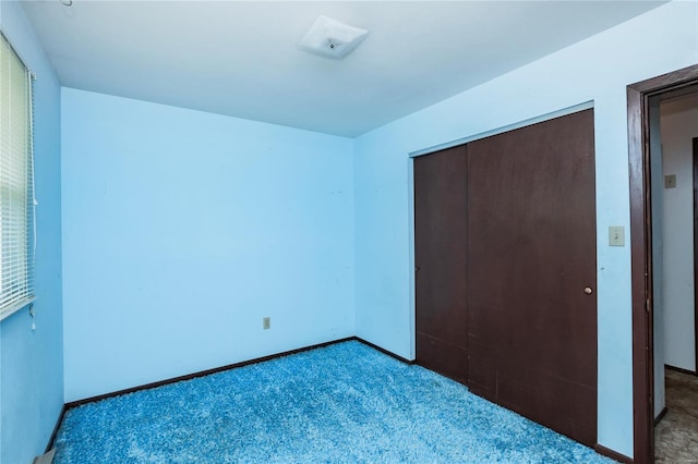 unfurnished bedroom featuring baseboards, carpet flooring, and a closet
