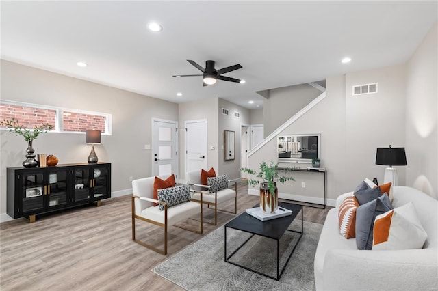 living area with a ceiling fan, visible vents, wood finished floors, and baseboards