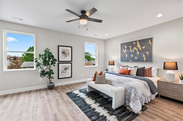 bedroom with visible vents, light wood-type flooring, baseboards, and multiple windows