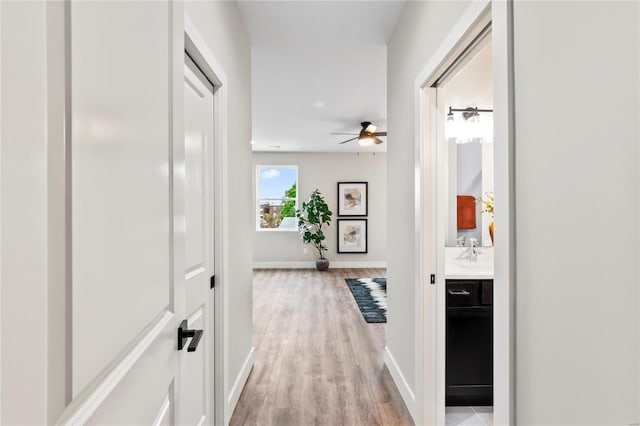 hall featuring light wood finished floors and baseboards