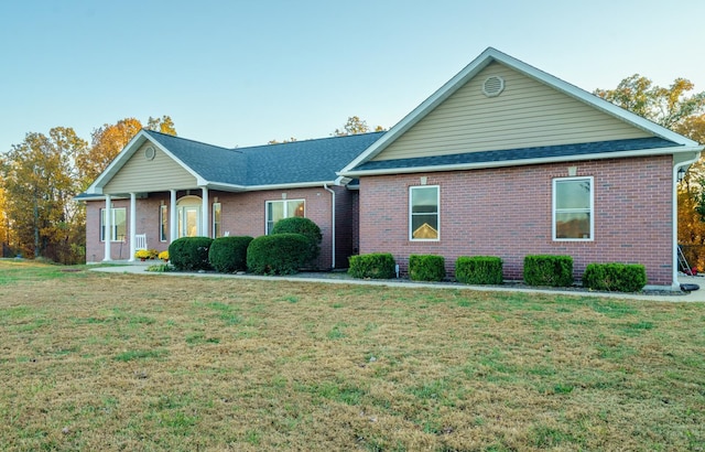 ranch-style home with a front yard, a shingled roof, and brick siding