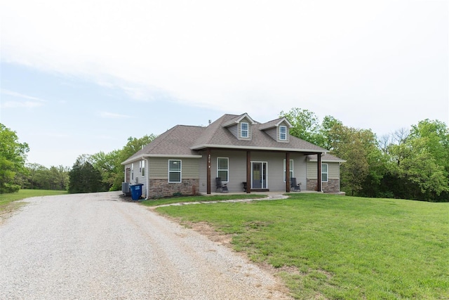 view of front facade featuring driveway, stone siding, and a front lawn