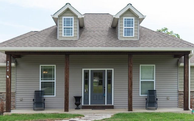 back of property with roof with shingles and a porch