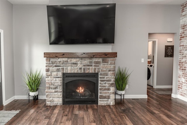 living room with baseboards, a warm lit fireplace, washer / clothes dryer, and wood finished floors