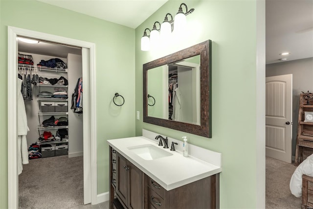 bathroom with vanity, baseboards, and a spacious closet