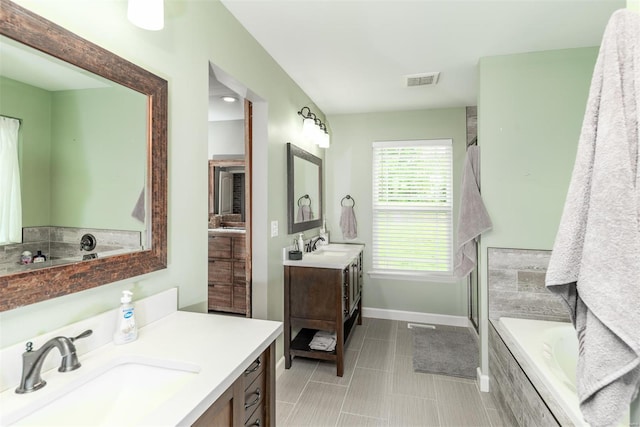 bathroom with a sink, baseboards, a washtub, and two vanities