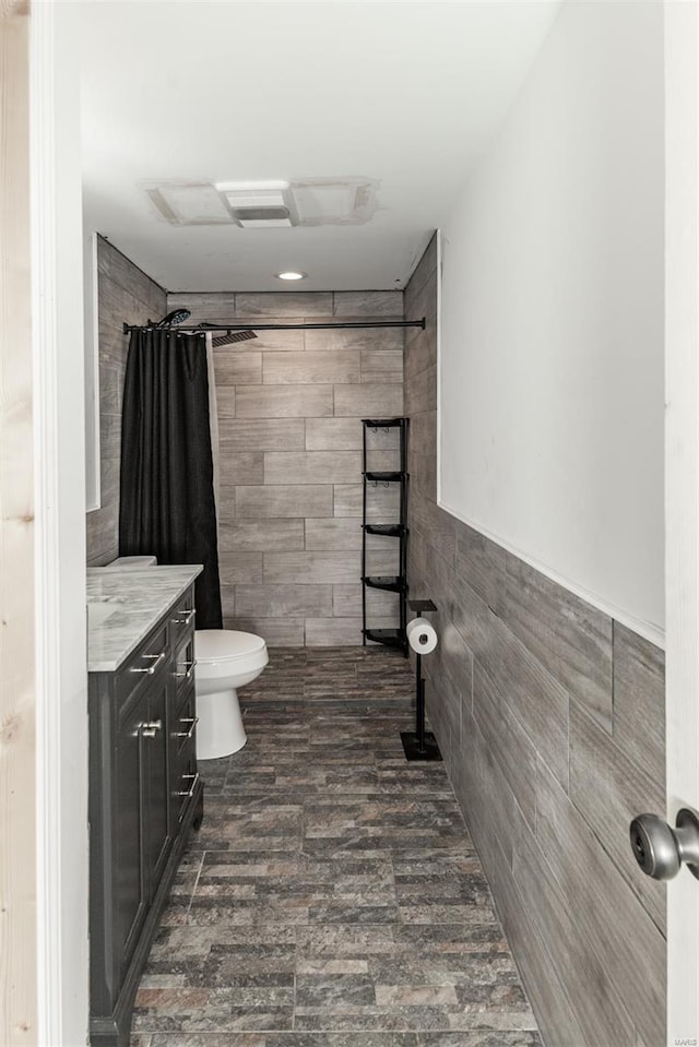 full bathroom with visible vents, tile walls, a tile shower, vanity, and toilet