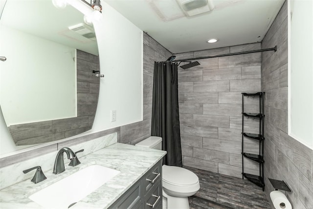 full bathroom with vanity, tile walls, a tile shower, and toilet