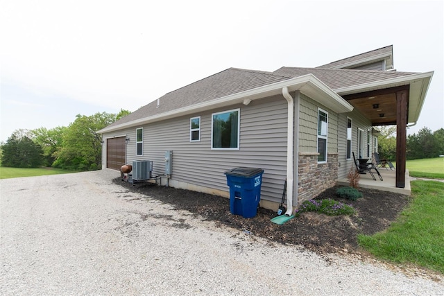 view of side of home featuring roof with shingles, stone siding, and cooling unit