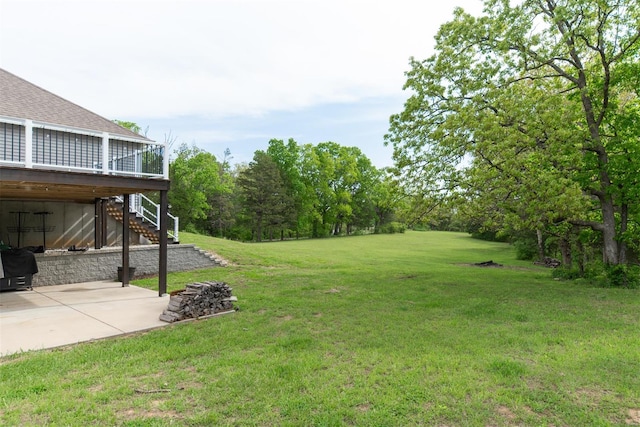 view of yard with a patio, a wooden deck, and stairway