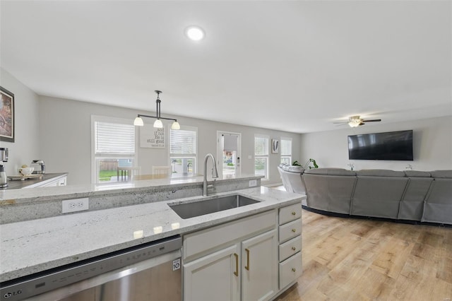 kitchen featuring decorative light fixtures, dishwasher, a sink, light stone counters, and white cabinetry