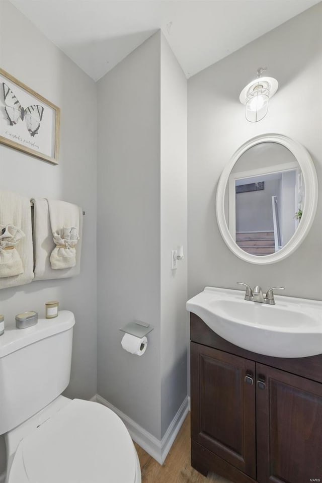 bathroom with baseboards, vanity, toilet, and wood finished floors