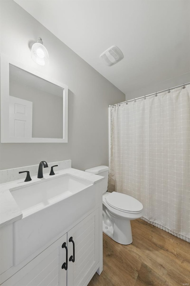 bathroom featuring toilet, visible vents, wood finished floors, and vanity