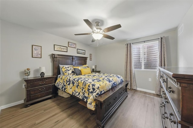 bedroom featuring baseboards, visible vents, ceiling fan, and light wood finished floors