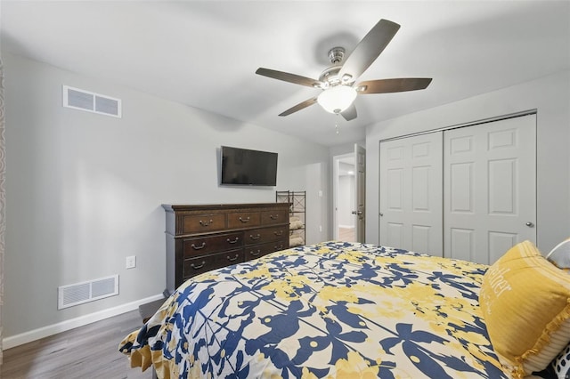 bedroom with baseboards, a closet, wood finished floors, and visible vents