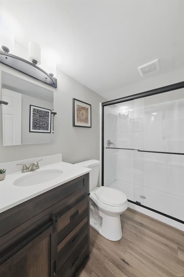 bathroom with visible vents, a stall shower, wood finished floors, vanity, and toilet