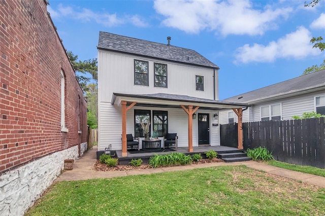 view of front of home featuring a front lawn, an outdoor living space, a shingled roof, and fence