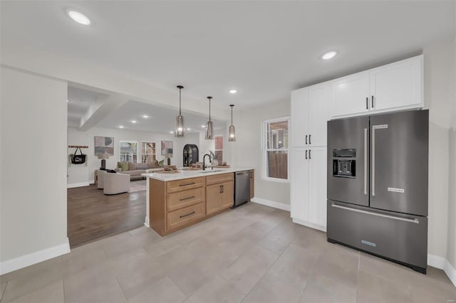 kitchen featuring a peninsula, stainless steel appliances, a sink, baseboards, and open floor plan