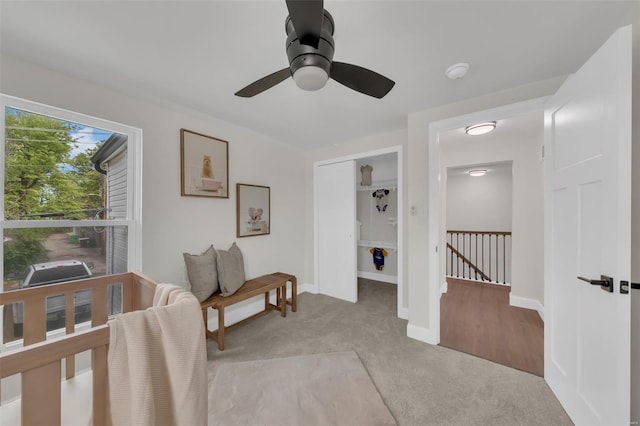 interior space with baseboards, a ceiling fan, and light colored carpet