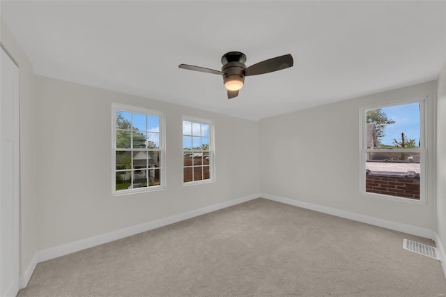 spare room with visible vents, ceiling fan, baseboards, and light carpet