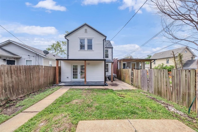 back of house with a patio, french doors, a fenced backyard, and a lawn