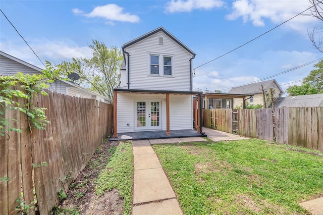back of house with a lawn, a patio, a fenced backyard, and french doors