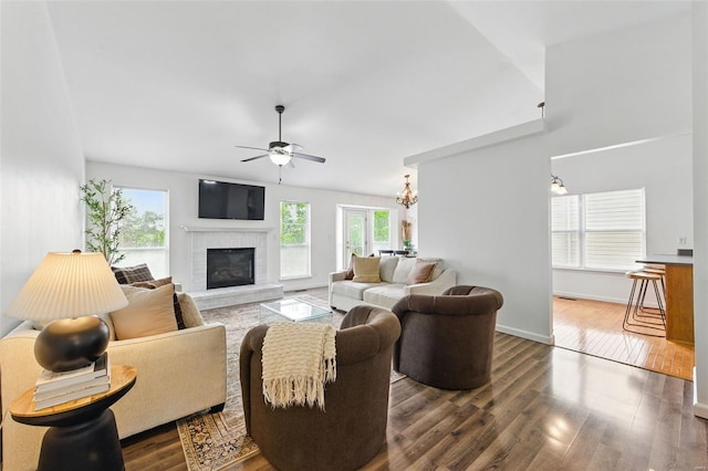 living room with baseboards, a fireplace, ceiling fan with notable chandelier, and wood finished floors