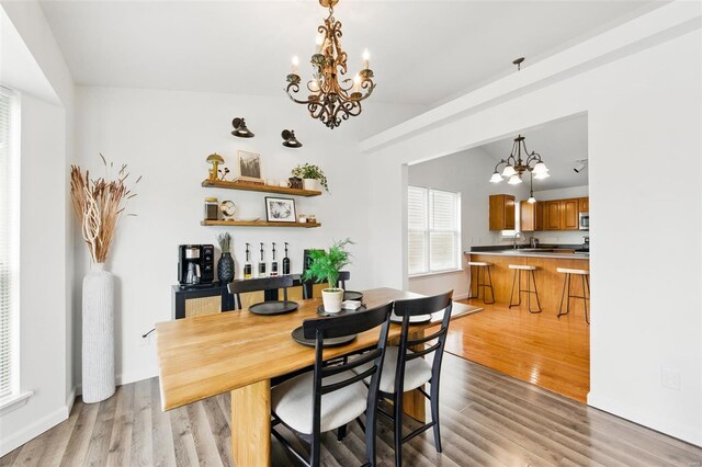 dining space featuring light wood finished floors and a notable chandelier