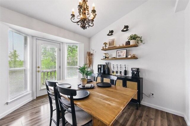 dining space with baseboards, lofted ceiling, wood finished floors, and a chandelier