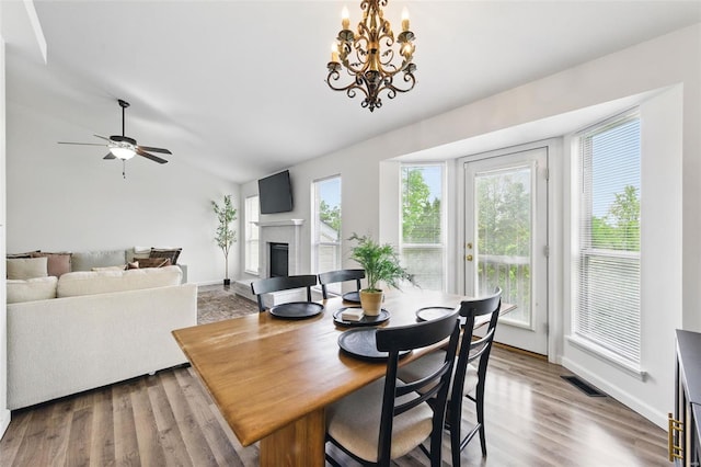 dining room featuring a brick fireplace, visible vents, plenty of natural light, and vaulted ceiling