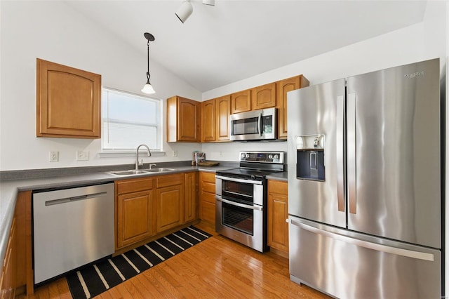 kitchen featuring light wood-type flooring, a sink, appliances with stainless steel finishes, and vaulted ceiling