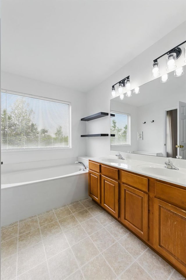 bathroom featuring double vanity, a sink, a bath, and tile patterned floors