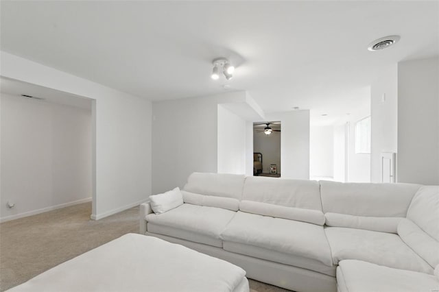 living room with baseboards, visible vents, a ceiling fan, and light colored carpet