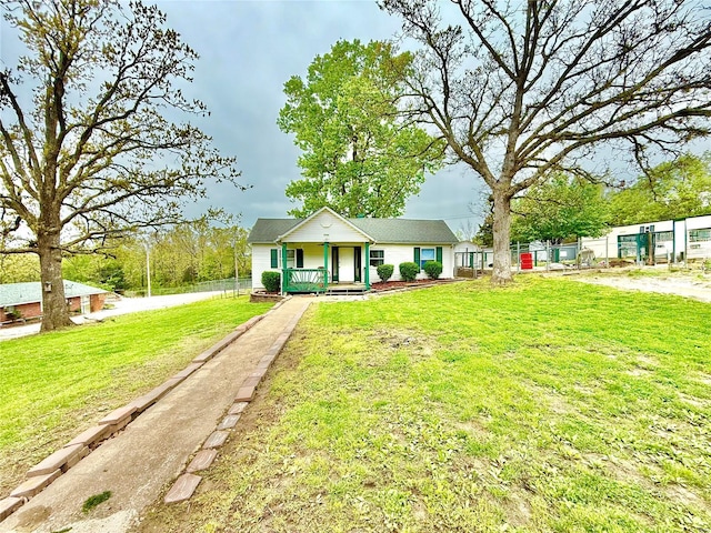 bungalow-style home featuring fence, covered porch, and a front yard