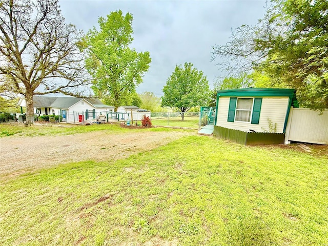 view of yard featuring a storage unit, fence, and an outbuilding