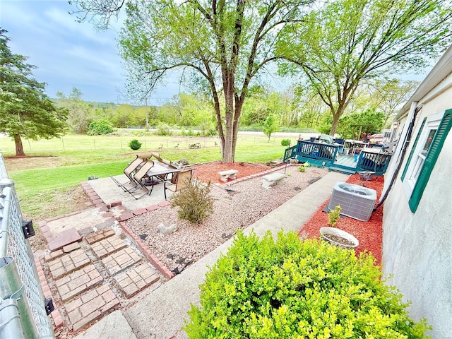 view of yard with a patio, a wooden deck, and central air condition unit
