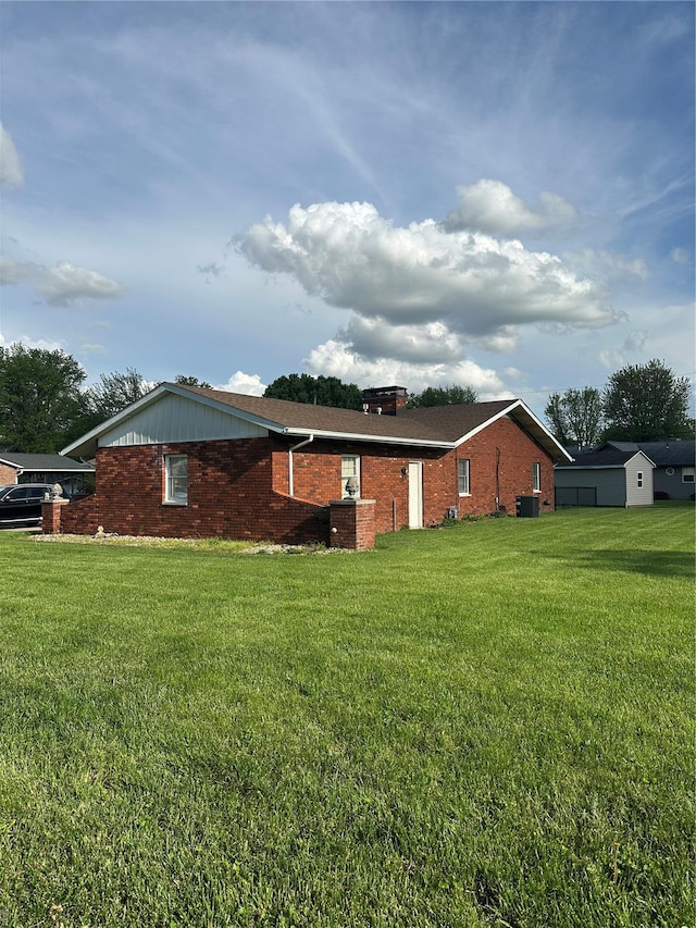 view of home's exterior with central AC unit, a chimney, a yard, and brick siding