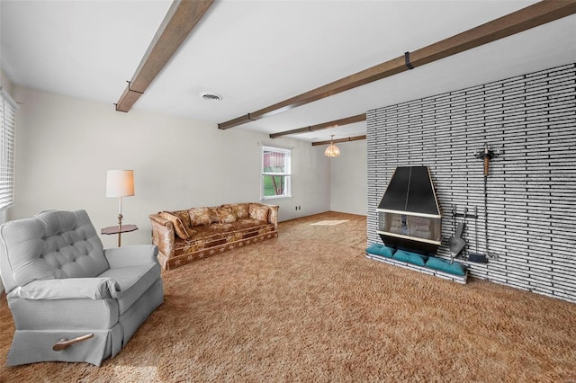 carpeted living room with visible vents, a wood stove, and beamed ceiling