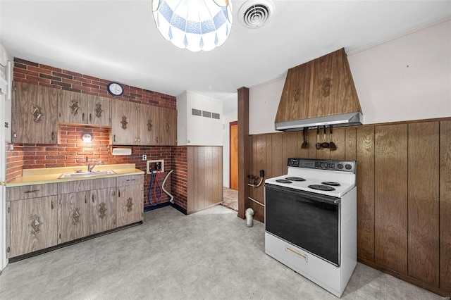 kitchen with visible vents, wood walls, white range with electric cooktop, light floors, and a sink