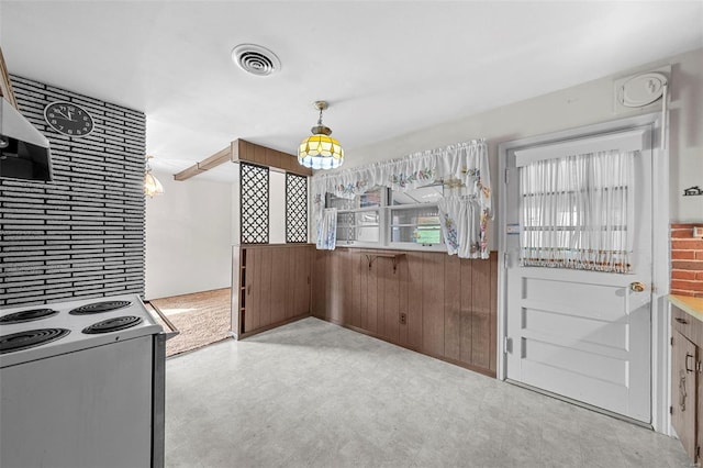 kitchen featuring visible vents, wood walls, electric range oven, and tile patterned floors