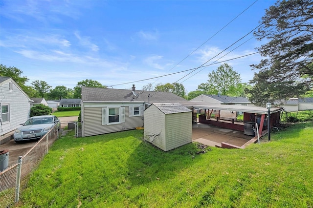 back of property with a storage unit, an outdoor structure, a lawn, and fence