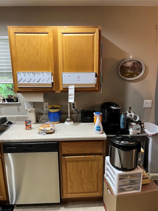 kitchen featuring stainless steel dishwasher, light countertops, and brown cabinetry
