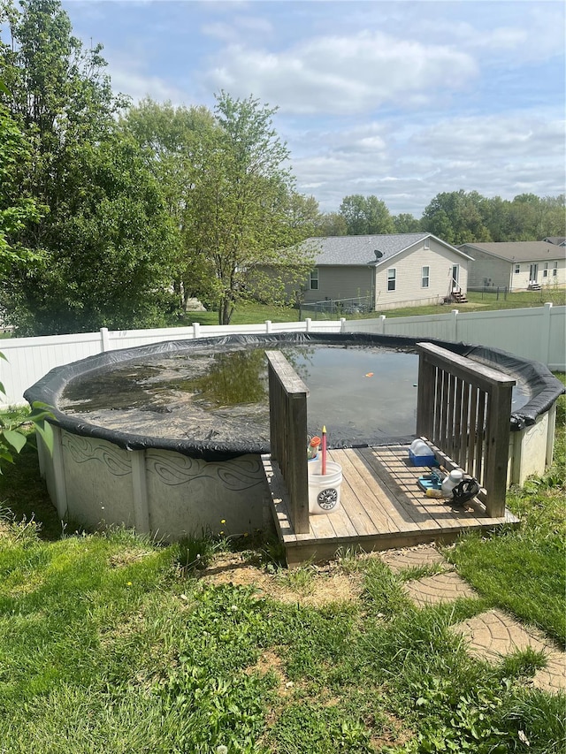 view of swimming pool featuring a wooden deck, a covered pool, and a fenced backyard
