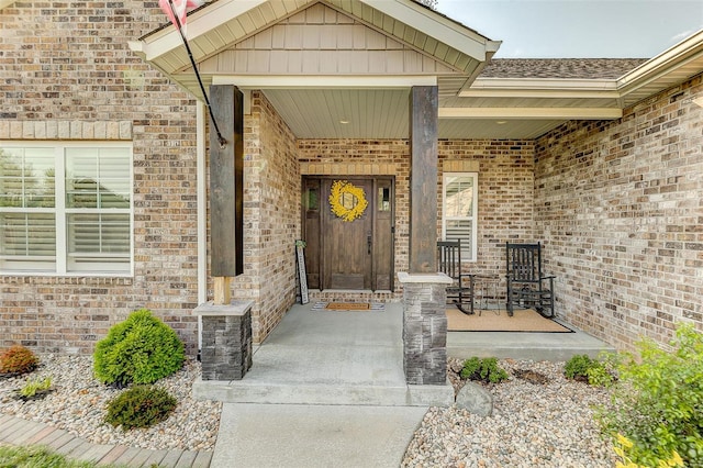doorway to property featuring a porch and brick siding