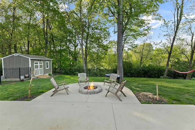view of patio / terrace with a fenced backyard, a fire pit, a shed, and an outbuilding
