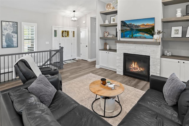 living area featuring baseboards, wood finished floors, and a fireplace