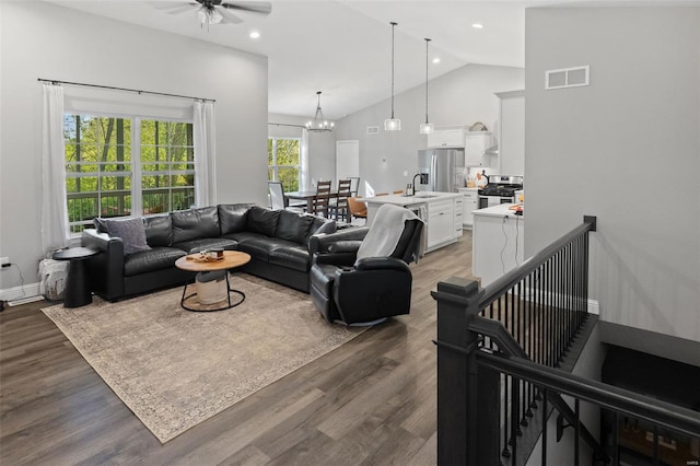 living room featuring visible vents, ceiling fan with notable chandelier, wood finished floors, and high vaulted ceiling