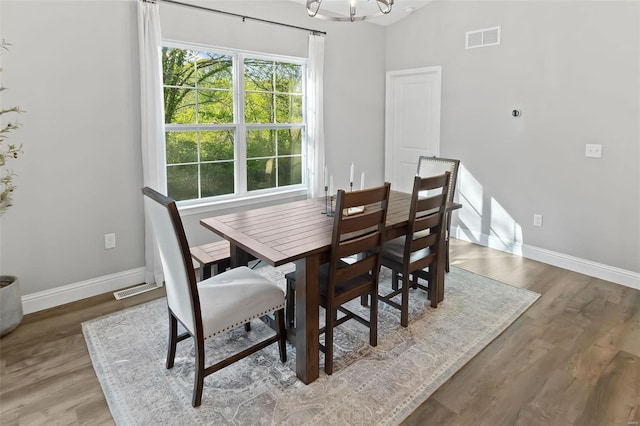 dining space featuring an inviting chandelier, baseboards, wood finished floors, and visible vents