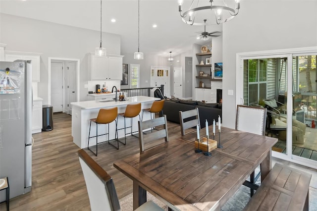 dining space with recessed lighting, high vaulted ceiling, ceiling fan with notable chandelier, and light wood-style floors